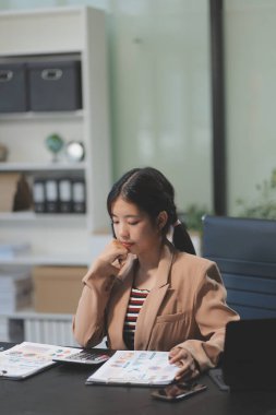 Telework konsepti - Asyalı iş kadını video toplantısına katılmak için dizüstü bilgisayar kullanır ve evdeki dijital tabletine notlar yazar