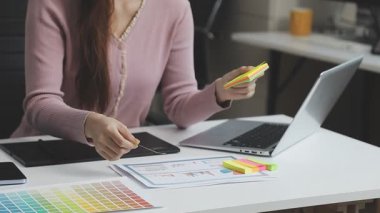 Modern ofiste renk tasarımı için tablet ve renk paleti kullanan genç kadın tasarımcı