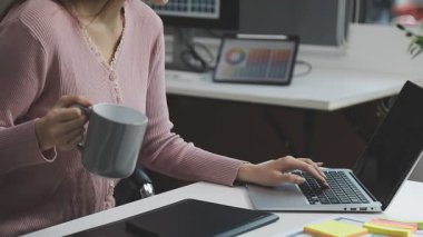 Genç iş kadını ofiste dizüstü bilgisayar kullanıyor..