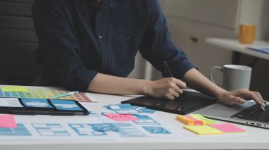 Genç bayan tasarımcı ofiste dizüstü bilgisayarda çalışıyor.