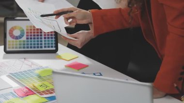 Genç iş kadını ofiste bilgisayarla uğraşırken yapışkan bir nota yazıyor.