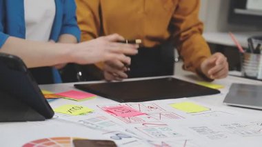 Gündelik giyinen genç iş adamı dizüstü bilgisayarda çalışıyor ve modern ofiste masa başında oturmuş fikirleri tartışıyor..