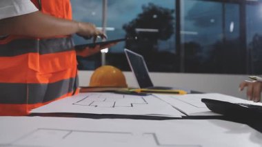 Ofisteki planlarla çalışan inşaat işçisi veya mühendisi.