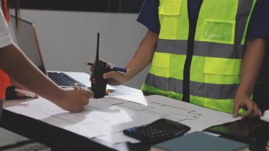 Güvenlik kasklı mühendis ve inşaat işçileri projeyi tartışıyorlar.