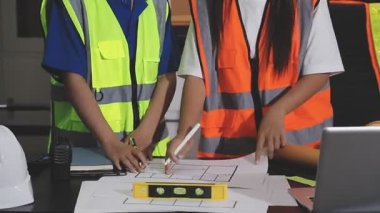 Ofiste planlarla çalışan Asyalı mühendis ya da mimar mühendisi.