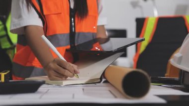 İnşaat alanındaki masanın planlarıyla çalışan kadın mühendis. Kapatın.