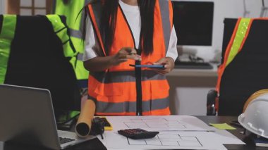 Ofisteki planlarla çalışan bir mühendis..