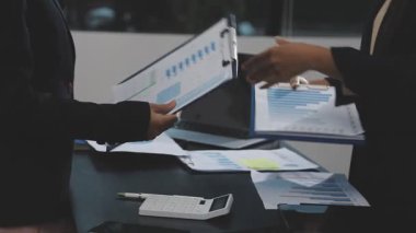 İş adamı ve iş kadını masanın üstünde bir belgeyle el sıkışıyor..