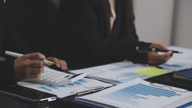 İş adamı masadaki hesap makinesi ve dizüstü bilgisayarla finansal grafiği analiz ediyor.