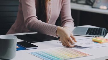 Ofiste grafik tasarımcısıyla çalışan genç bir kadın..