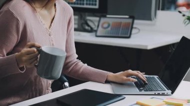 Dizüstü bilgisayar kullanan ve klavyede daktilo kullanan genç iş kadınını kapatın.