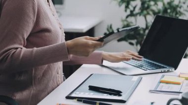 Modern ofiste akıllı telefon kullanan genç bir kadın. Genç bir kadın dizüstü bilgisayarla çalışıyor..