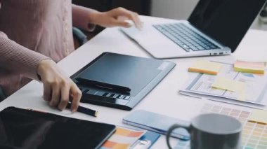 Bilgisayarlı ve akıllı telefonlu bir kadın ofiste çalışıyor.