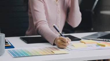 Genç bayan tasarımcı ofis masasında oturuyor.