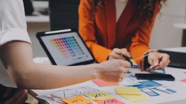 Genç bayan tasarımcı iş yerinde tablet üzerinde çalışıyor.