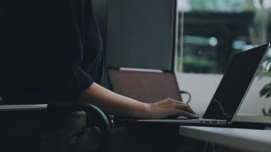 Genç Asyalı kadın ofiste dizüstü bilgisayarla çalışıyor.