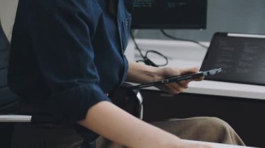 Ofiste bilgisayarla çalışırken elinde akıllı telefon tutan genç adamın yakın görüntüsü