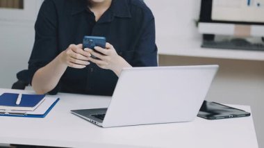 Laptop ve telefon kullanan genç bir iş kadını.