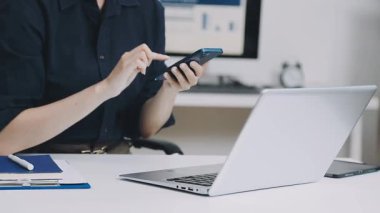 Günlük kıyafetlerle genç bir kadın ofiste bilgisayar başında oturuyor ve çalışıyor..