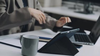 İş adamı bir kahve dükkanında otururken dizüstü bilgisayar kullanıyor ve kahve içiyor..