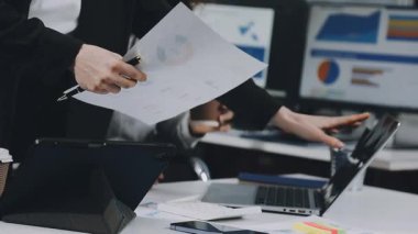 Genç iş kadınları dizüstü bilgisayar kullanıyor ve modern bir ofiste deftere yazı yazıyorlar..