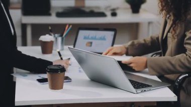 İş kadını laptopunu kullanıyor ve ofiste kahve içiyor.