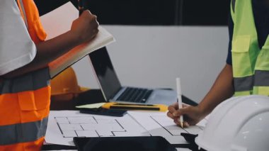 İnşaat alanında dizüstü bilgisayarı ve planı olan genç bir mimar mühendisi..