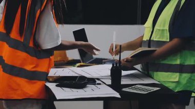 Asyalı mühendis ya da mimar inşaat alanında plan üzerinde çalışıyor.