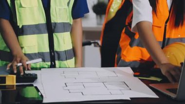 Asyalı mühendis ekip mühendisi inşaat planıyla birlikte çalışıyor..