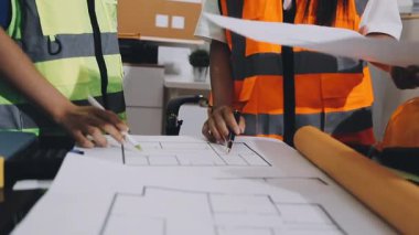 Asyalı mühendis mühendis. Odadaki inşaat alanında yeni bir proje üzerinde çalışıyorlar..