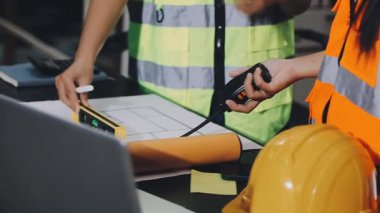 İnşaat projesi veya fabrika için elinde tabletle sarı miğferli mühendis ya da mühendis kadın işçi..
