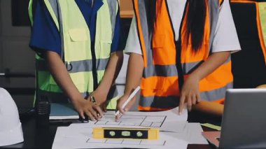 İki genç Asyalı mimar inşaat alanında proje üzerinde çalışıyor..