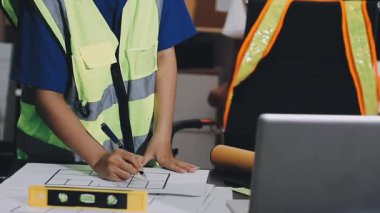 İnşaat alanında dizüstü bilgisayarı ve planı olan Asyalı mühendis ya da mühendis..