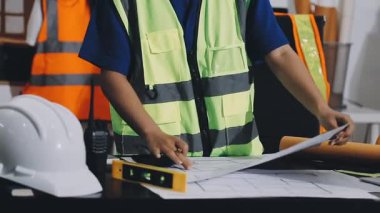 Asyalı mühendis planlarla ofiste çalışıyor.