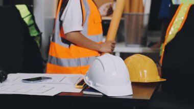 Miğferli ve koruyucu giysili kadın mimar arka plandaki projenin planıyla çalışıyor. inşaat kavramı