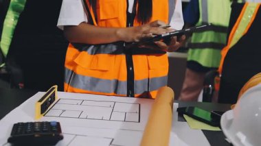 İnşaat üniforması içindeki mühendis kadın mühendis planlı, ofiste çalışıyor. İnşaat alanında çalışan mühendis, seçici odaklı.