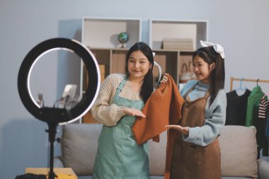 Genç Asyalı kadınlar müşterilerden gelen yeni siparişten sonra mutlu olurlar. Asyalı bir kadının online mağazasının satışındaki başarısının sürpriz ve şok edici yüzü. Çevrimiçi satış. Çevrimiçi Alışveriş