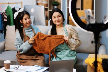 Genç Asyalı kadınlar müşterilerden gelen yeni siparişten sonra mutlu olurlar. Asyalı bir kadının online mağazasının satışındaki başarısının sürpriz ve şok edici yüzü. Çevrimiçi satış. Çevrimiçi Alışveriş