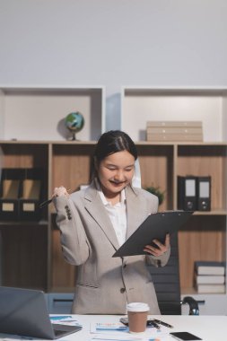 Asyalı iş kadını şirketin başarısı hakkında mutlu bir şekilde çalışıyor, finansal raporu analiz etmeyi planlıyor, iş planı yatırımı, finans analizi kavramı.