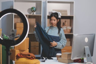 Genç Asyalı kadınlar müşterilerden gelen yeni siparişten sonra mutlu olurlar. Asyalı bir kadının online mağazasının satışındaki başarısının sürpriz ve şok edici yüzü. Çevrimiçi satış. Çevrimiçi Alışveriş