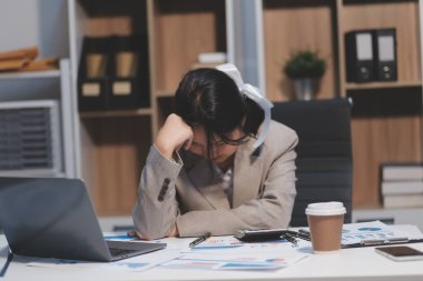 Genç Asyalı kadın migren ağrısı çekiyor. Ofiste dizüstü bilgisayarla çalışırken çok çalışan iş kadını finansörü..