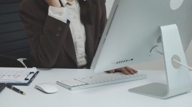 Beyaz gömlekli genç bir kadın bilgisayarla çalışıyor.