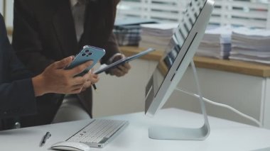 Ofiste çalışan genç işadamı, akıllı telefon ve tablet kullanıyor.