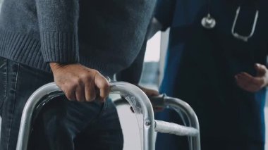 Tekerlekli sandalyedeki adam arka planda el ele tutuşuyor.