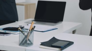 Ofiste dizüstü bilgisayar ve akıllı telefon kullanan bir işadamı.