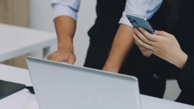 Ofisteki masada akıllı telefon ve dizüstü bilgisayar kullanan iş adamları..