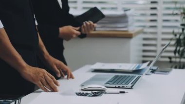 Modern ofiste dizüstü bilgisayar ve belgelerle çalışan genç bir iş adamı.