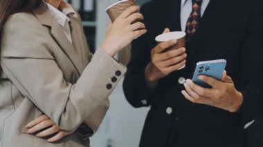 İş kadını ofisinde kahve içerken akıllı telefon kullanıyor.