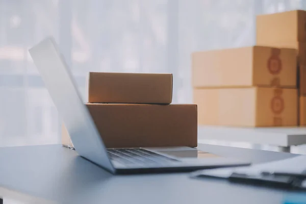 stock image Startup small business entrepreneur or freelance Asian woman using a laptop with box, Young success Asian woman with her hand lift up, online marketing packaging box and delivery, SME concept.