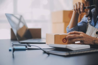 Küçük işletme girişimcisi ya da serbest çalışan, kutulu laptop kullanan Asyalı bir kadın, elini kaldıran genç başarılı Asyalı kadın, çevrimiçi pazarlama kutusu ve teslimatı, KME konsepti.